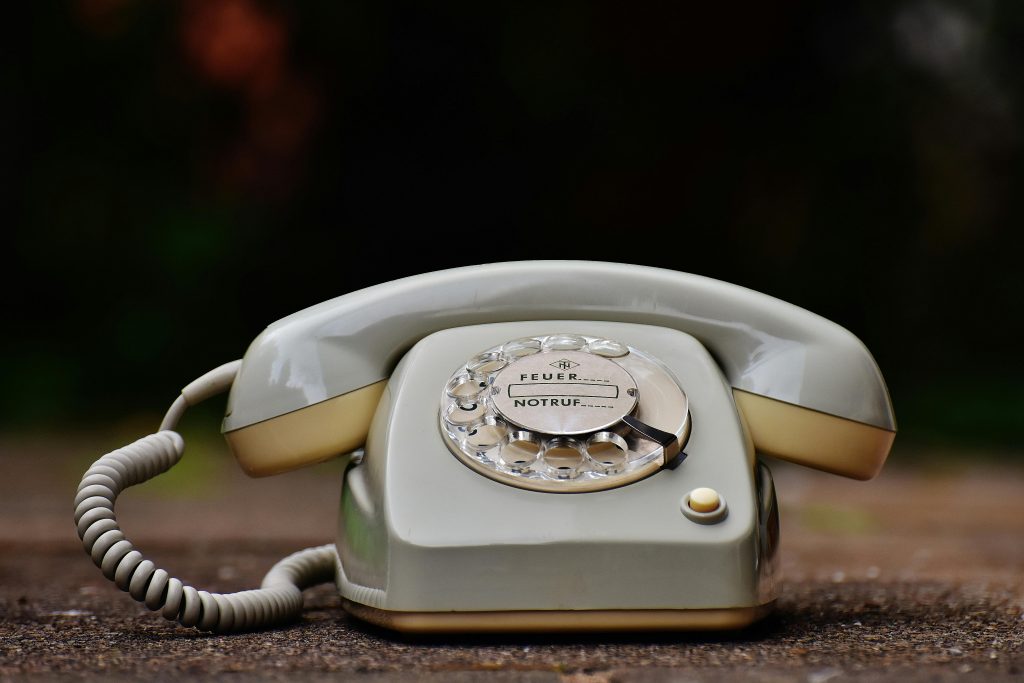 Gray rotary telephone on brown surface